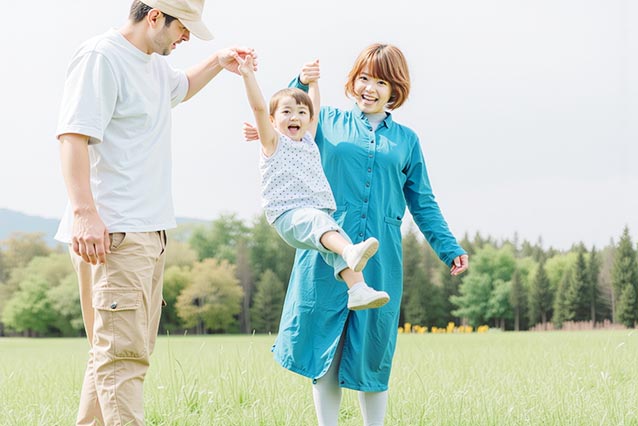 両親と手をつないで元気にジャンプする子供の笑顔